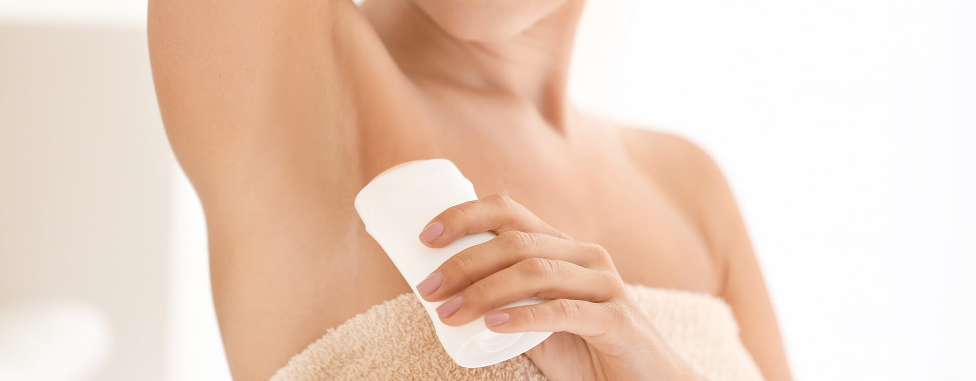 Persona che si mette il deodorante stick realizzato attraverso il servizio di produzione di cosmetici solidi.